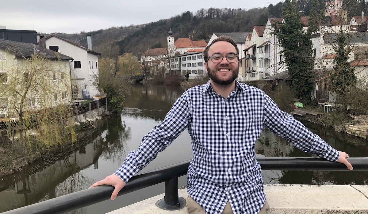 Student Will McGowan smiling broadly in front of a canal